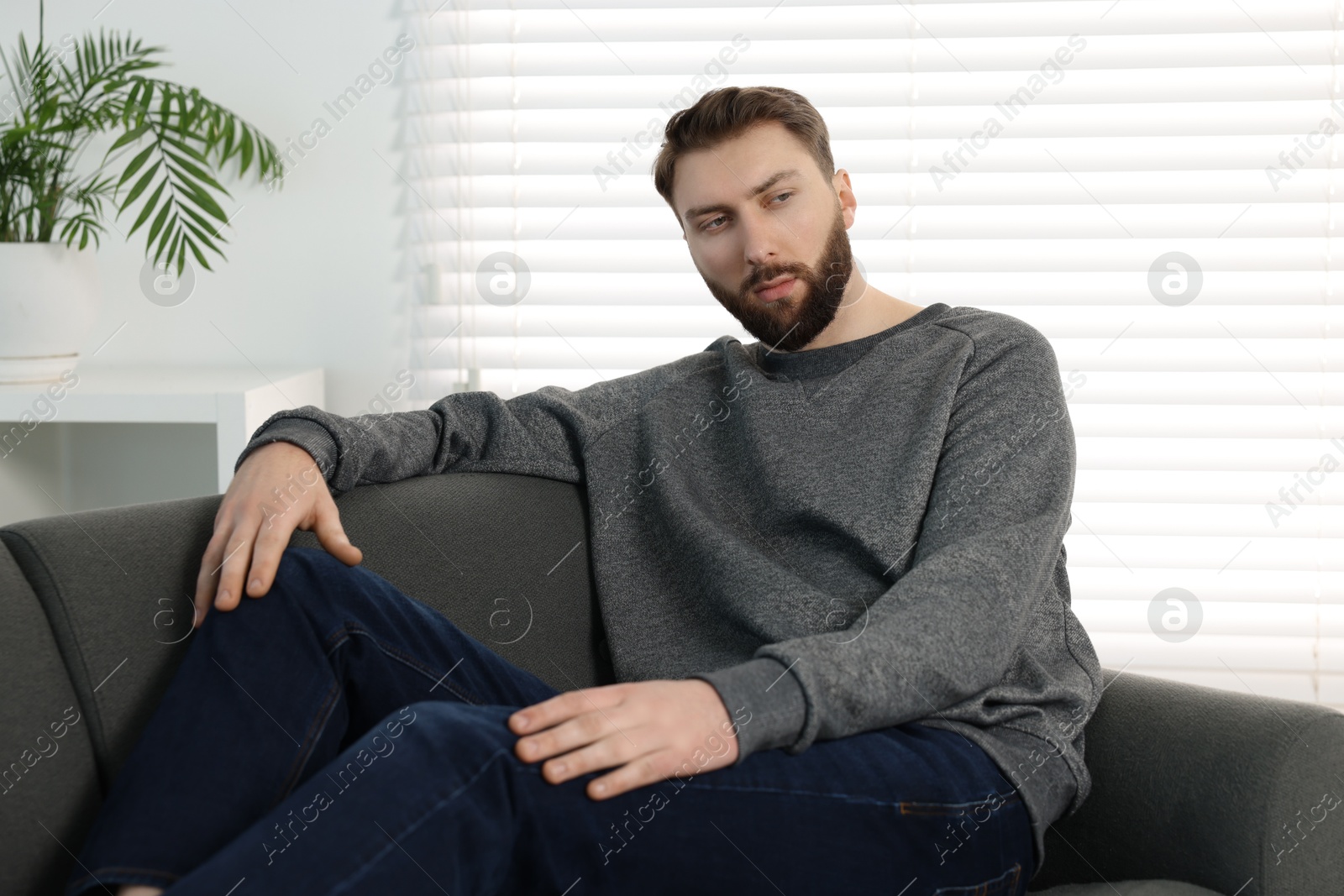 Photo of Loneliness concept. Sad man sitting on sofa at home