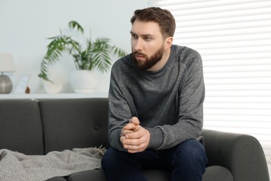 Loneliness concept. Sad man sitting on sofa at home