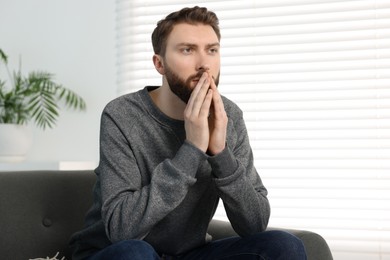 Loneliness concept. Sad man sitting on sofa at home