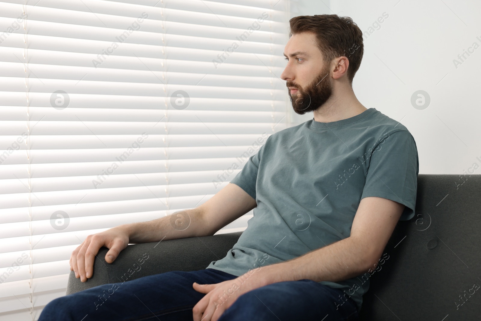 Photo of Loneliness concept. Sad man sitting on sofa at home