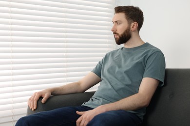 Photo of Loneliness concept. Sad man sitting on sofa at home