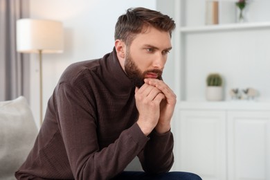 Photo of Loneliness concept. Sad man sitting on sofa at home