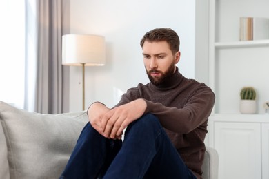 Photo of Loneliness concept. Sad man sitting on sofa at home