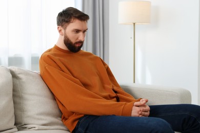 Photo of Loneliness concept. Sad man sitting on sofa at home