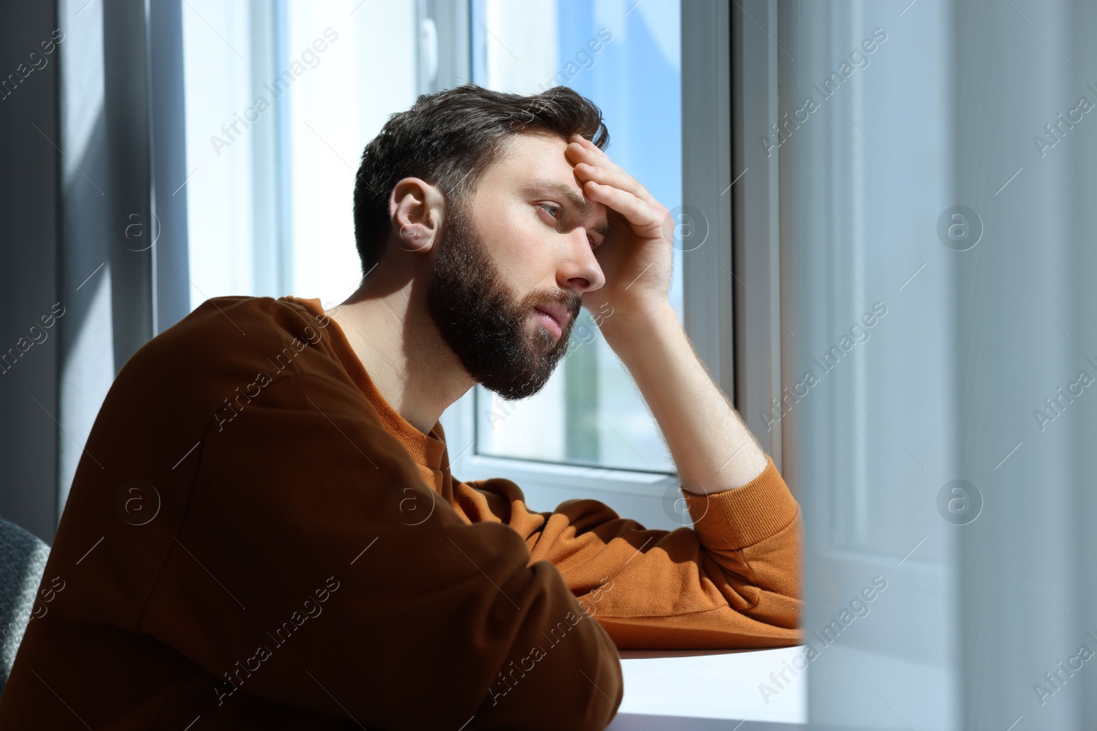 Photo of Loneliness concept. Sad man near window at home