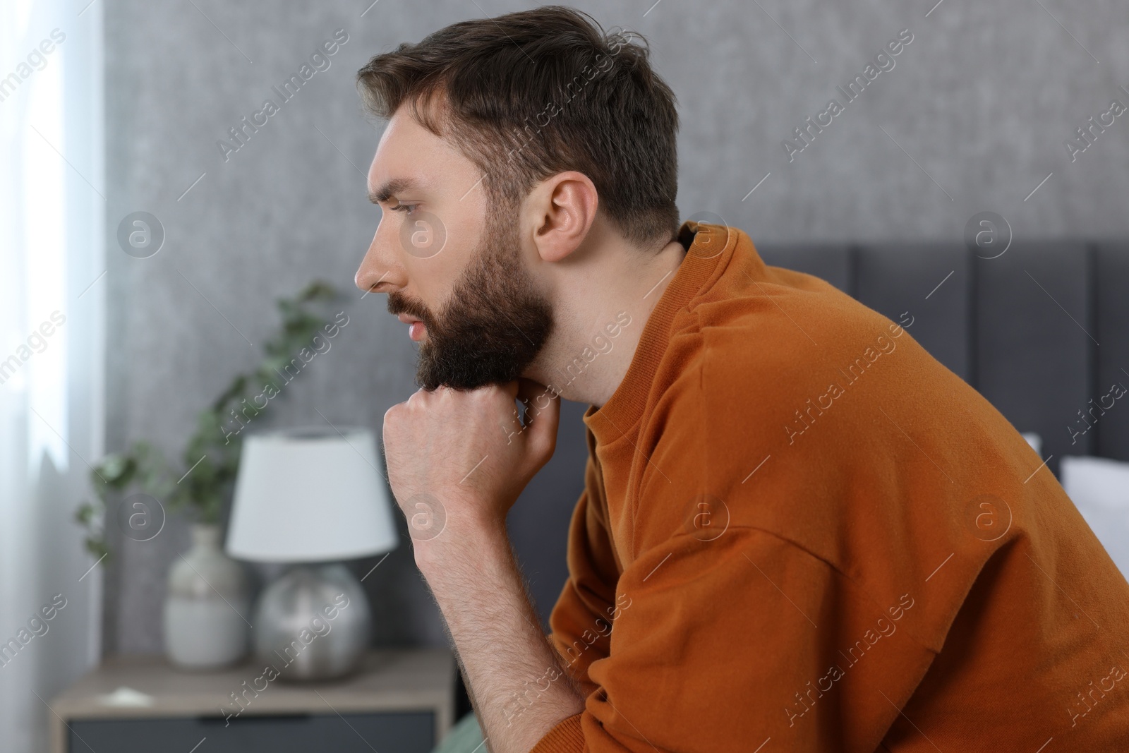 Photo of Loneliness concept. Sad man sitting on bed at home