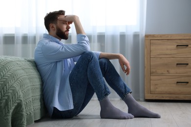 Photo of Loneliness concept. Sad man sitting on floor at home