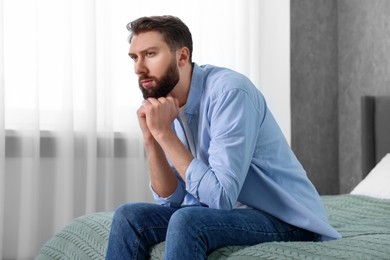 Photo of Loneliness concept. Sad man sitting on bed at home