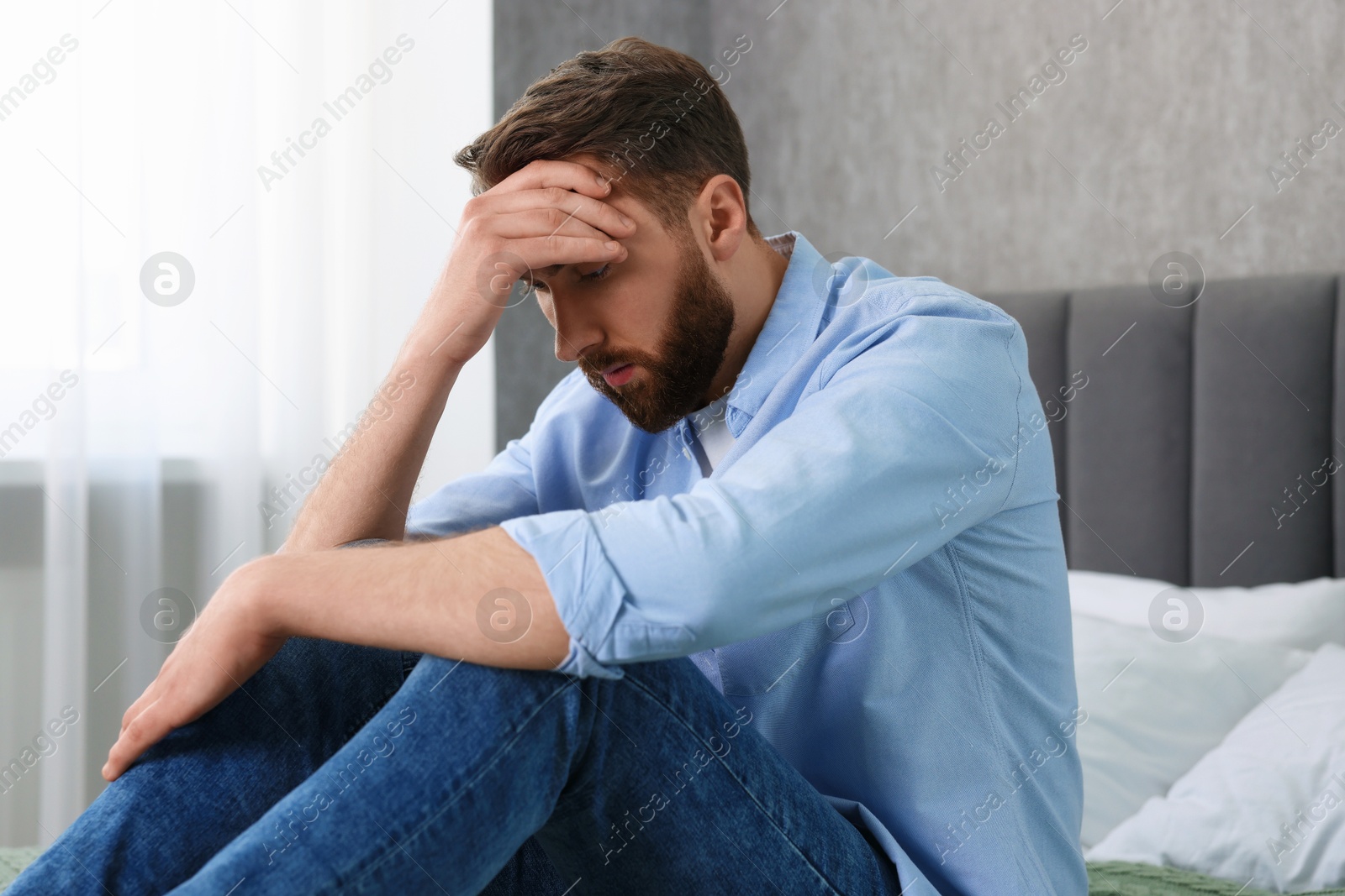 Photo of Loneliness concept. Sad man sitting on bed at home