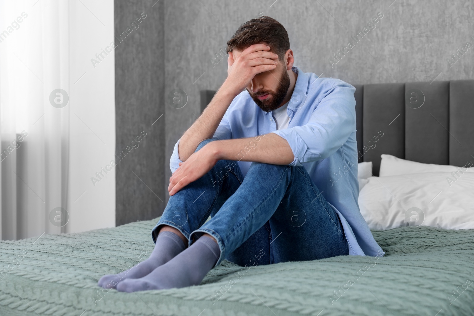 Photo of Loneliness concept. Sad man sitting on bed at home