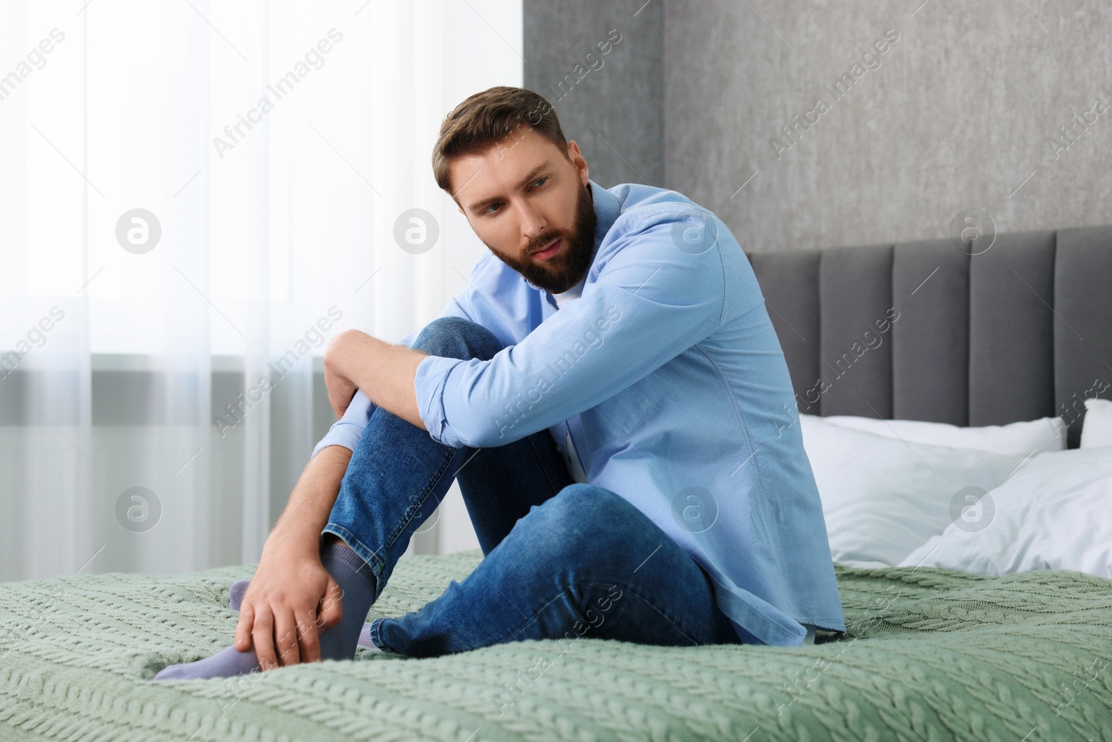 Photo of Loneliness concept. Sad man sitting on bed at home