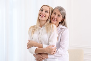 Photo of Family portrait of young woman and her mother near white wall