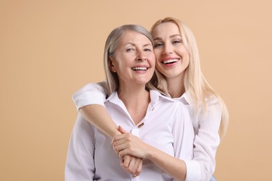 Photo of Family portrait of young woman and her mother on beige background