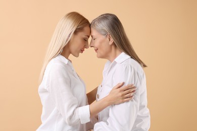 Family portrait of young woman and her mother on beige background