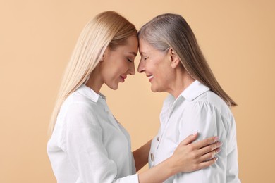 Family portrait of young woman and her mother on beige background