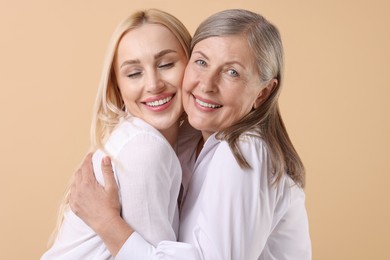 Photo of Family portrait of young woman and her mother on beige background