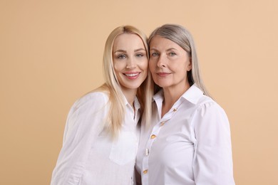 Photo of Family portrait of young woman and her mother on beige background