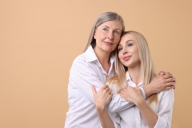 Family portrait of young woman and her mother on beige background. Space for text