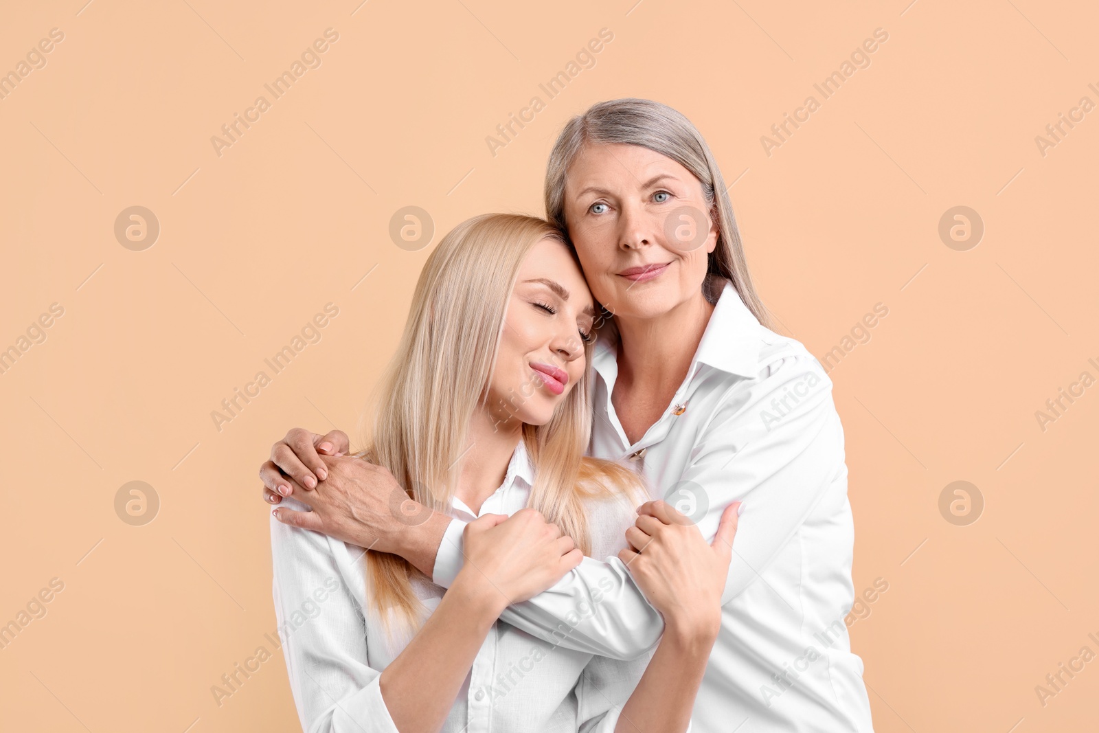 Photo of Family portrait of young woman and her mother on beige background