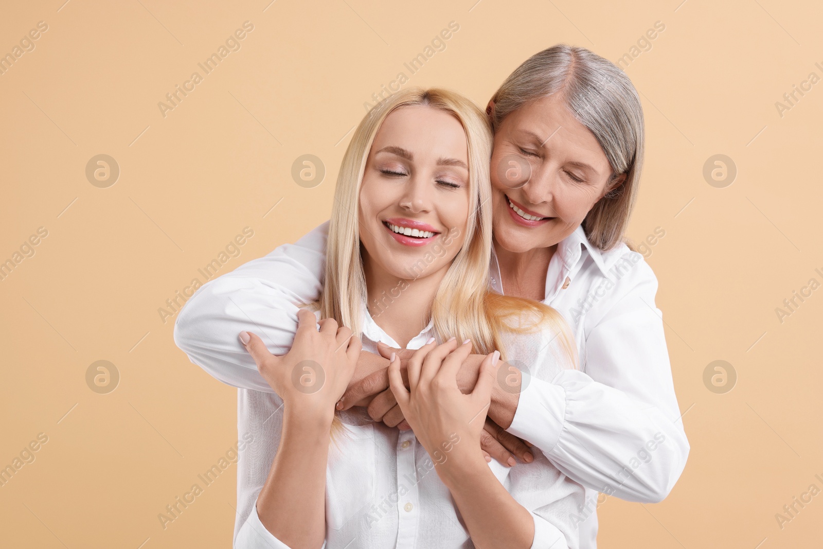 Photo of Family portrait of young woman and her mother on beige background