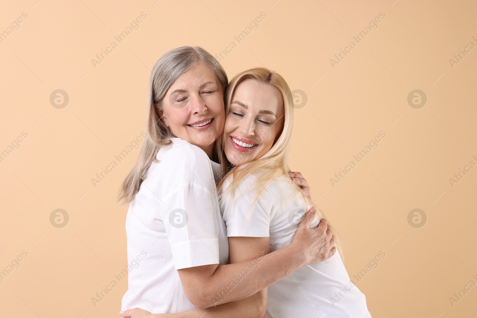 Photo of Family portrait of young woman and her mother on beige background