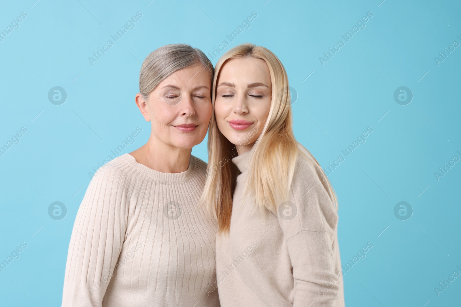 Photo of Family portrait of young woman and her mother on light blue background