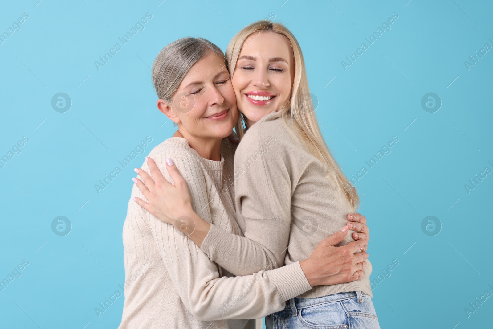 Photo of Family portrait of young woman and her mother on light blue background