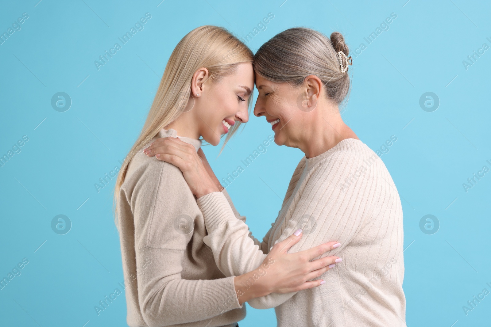 Photo of Family portrait of young woman and her mother on light blue background