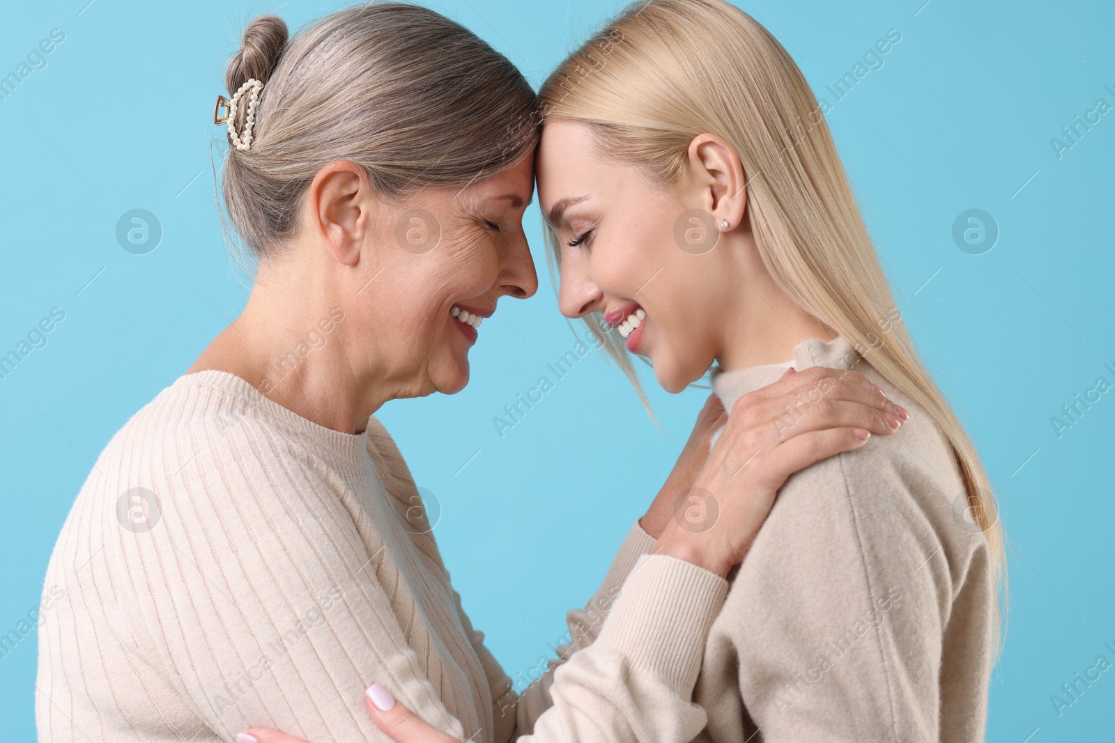 Photo of Family portrait of young woman and her mother on light blue background