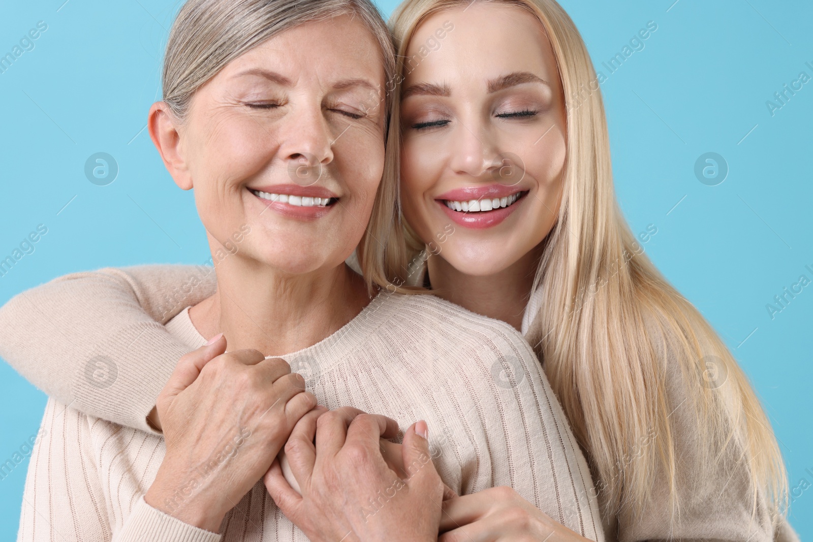 Photo of Family portrait of young woman and her mother on light blue background