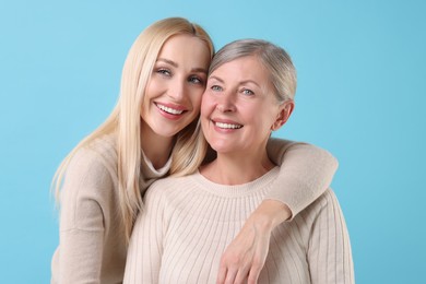 Photo of Family portrait of young woman and her mother on light blue background