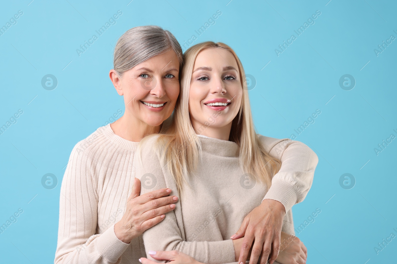 Photo of Family portrait of young woman and her mother on light blue background