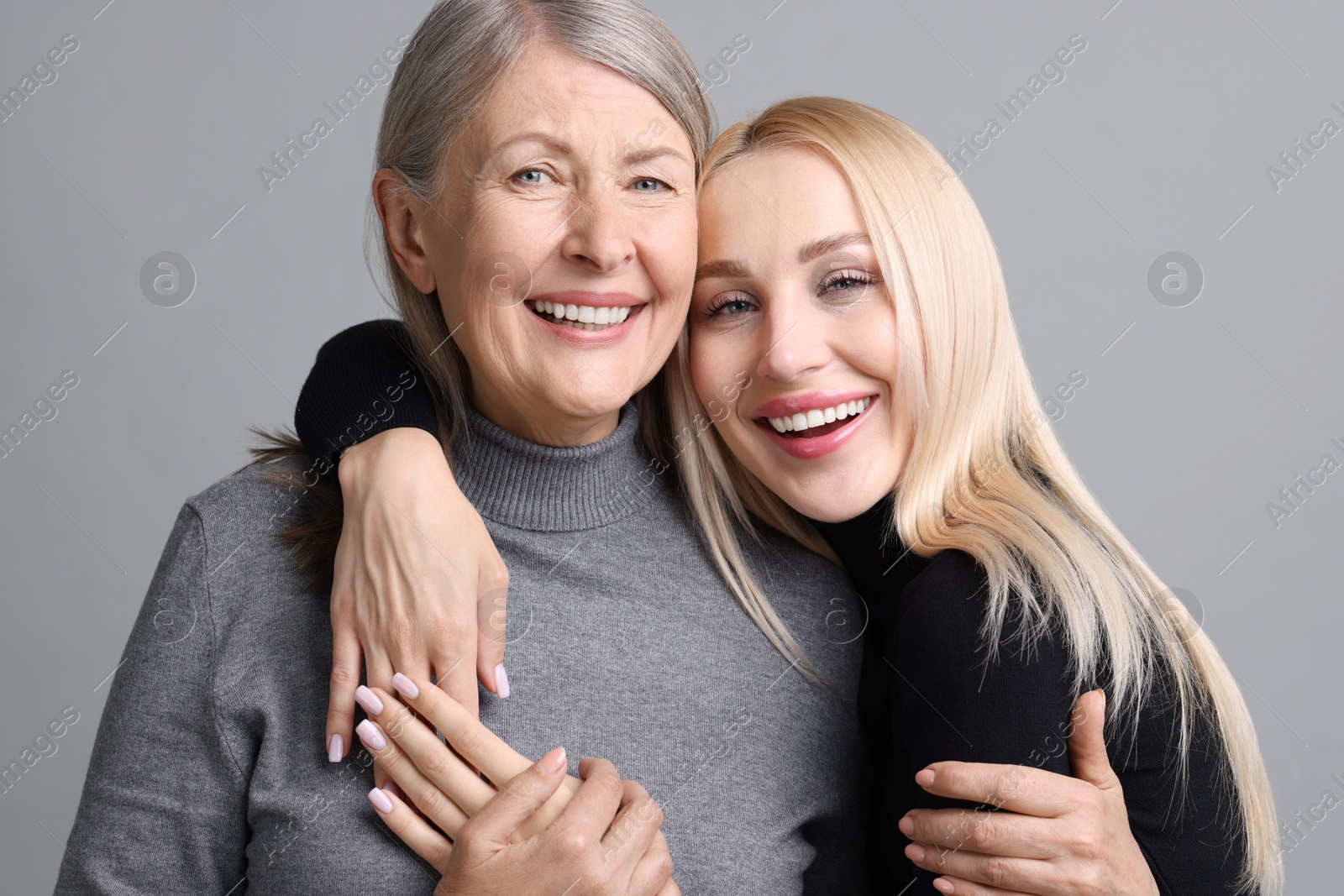 Photo of Family portrait of young woman and her mother on grey background