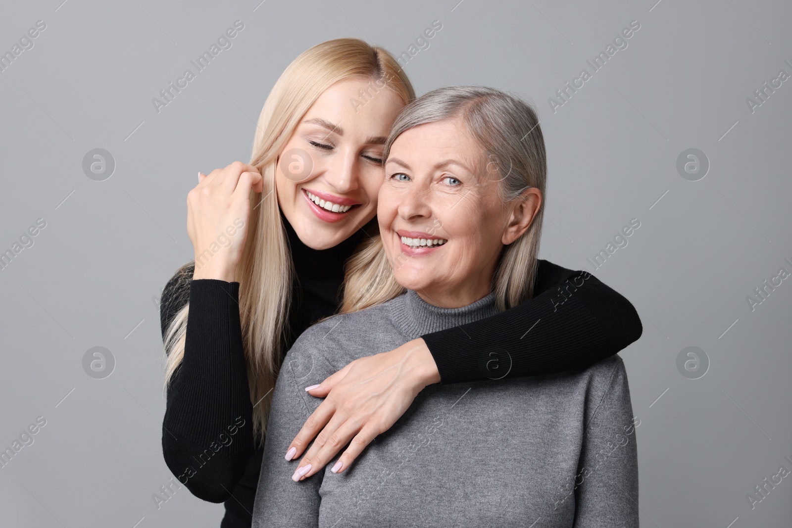 Photo of Family portrait of young woman and her mother on grey background