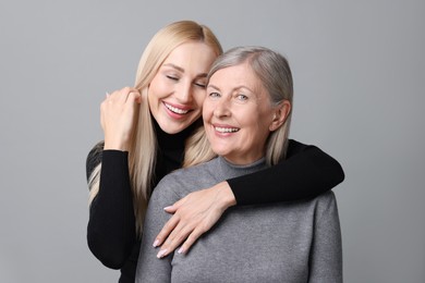 Photo of Family portrait of young woman and her mother on grey background