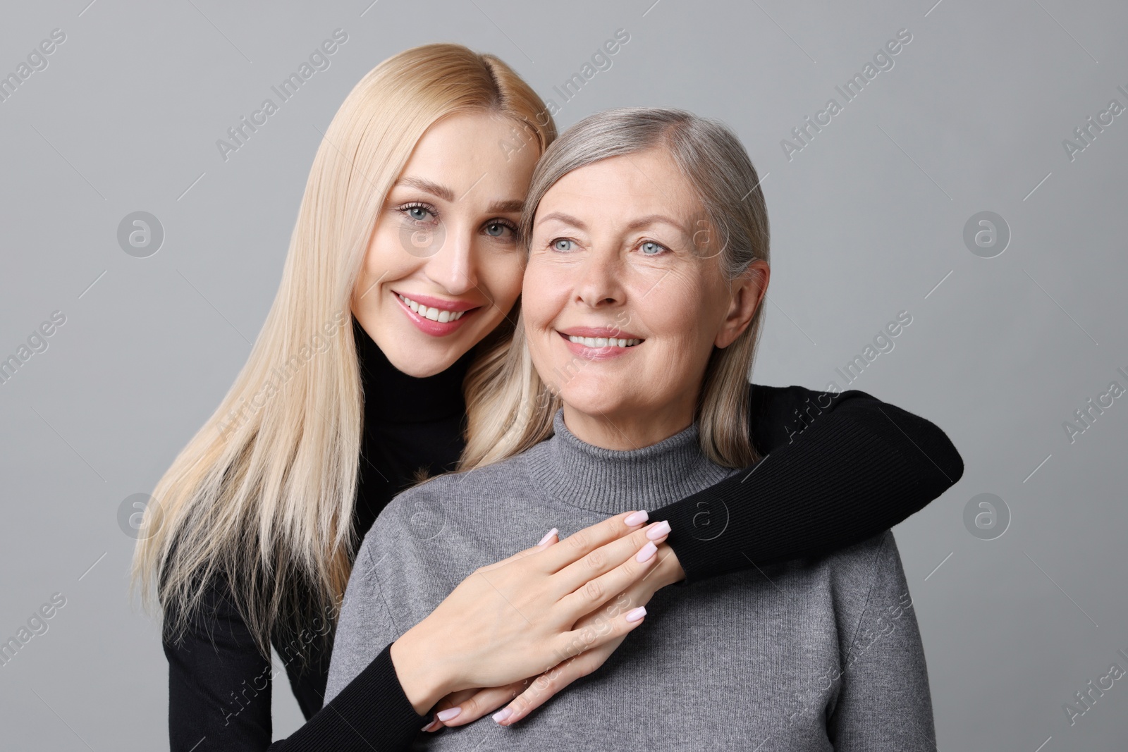 Photo of Family portrait of young woman and her mother on grey background