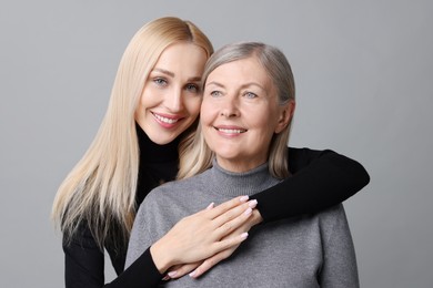 Photo of Family portrait of young woman and her mother on grey background