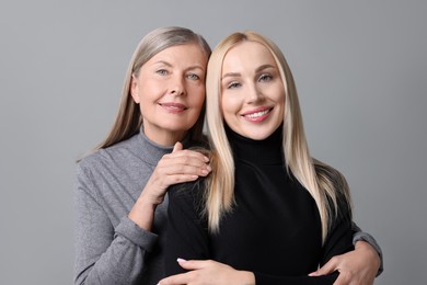 Photo of Family portrait of young woman and her mother on grey background