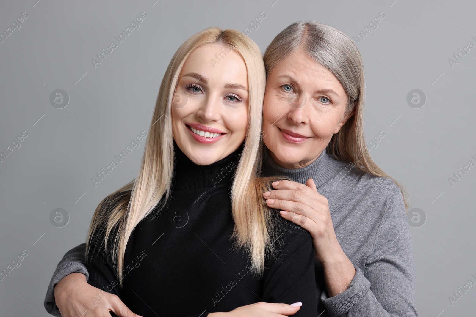 Photo of Family portrait of young woman and her mother on grey background