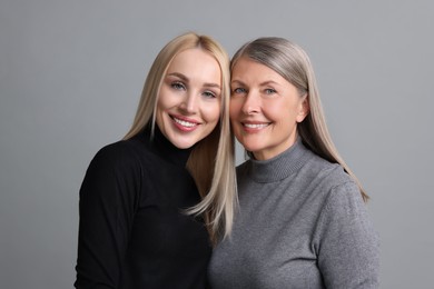 Photo of Family portrait of young woman and her mother on grey background