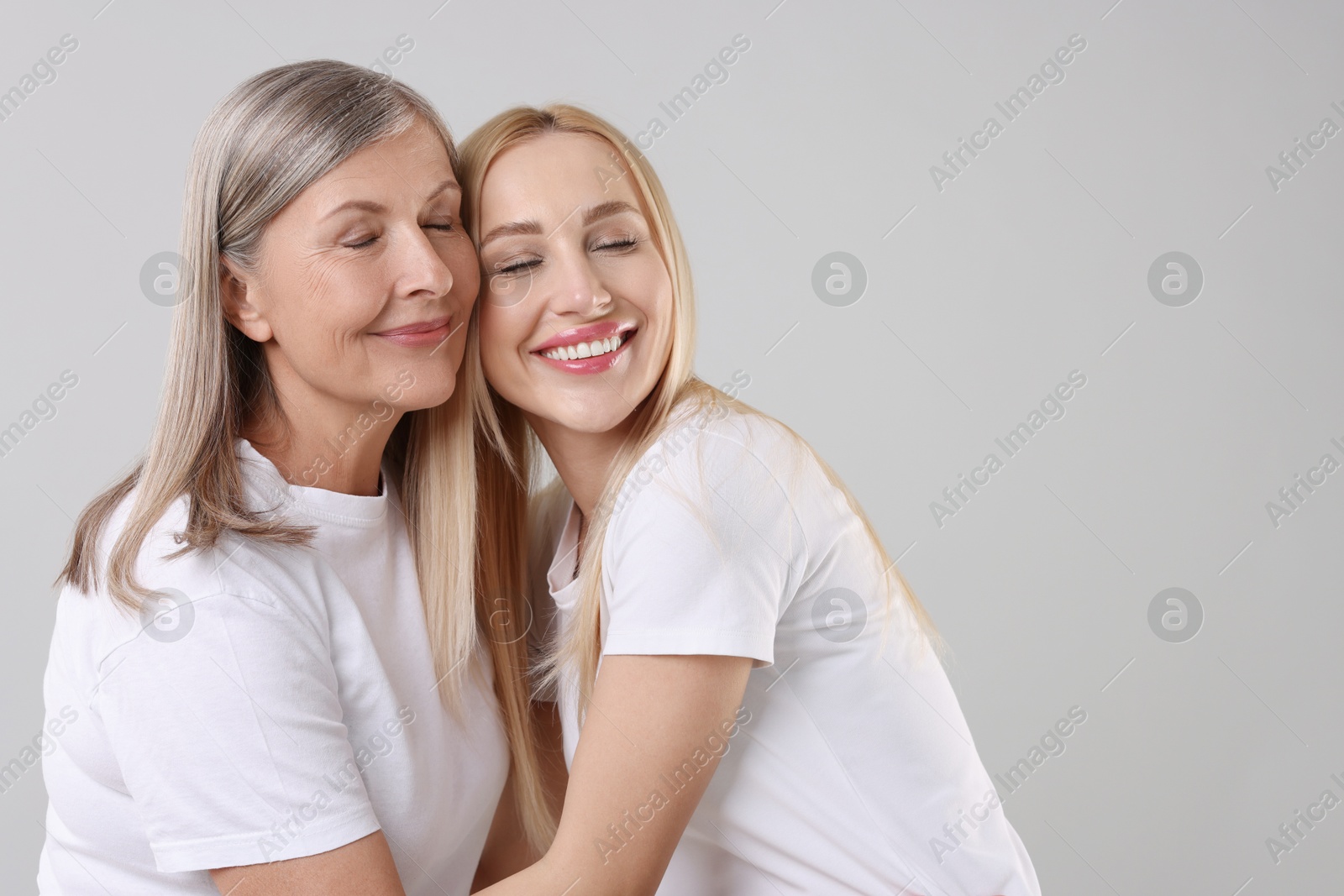 Photo of Family portrait of young woman and her mother on light grey background. Space for text