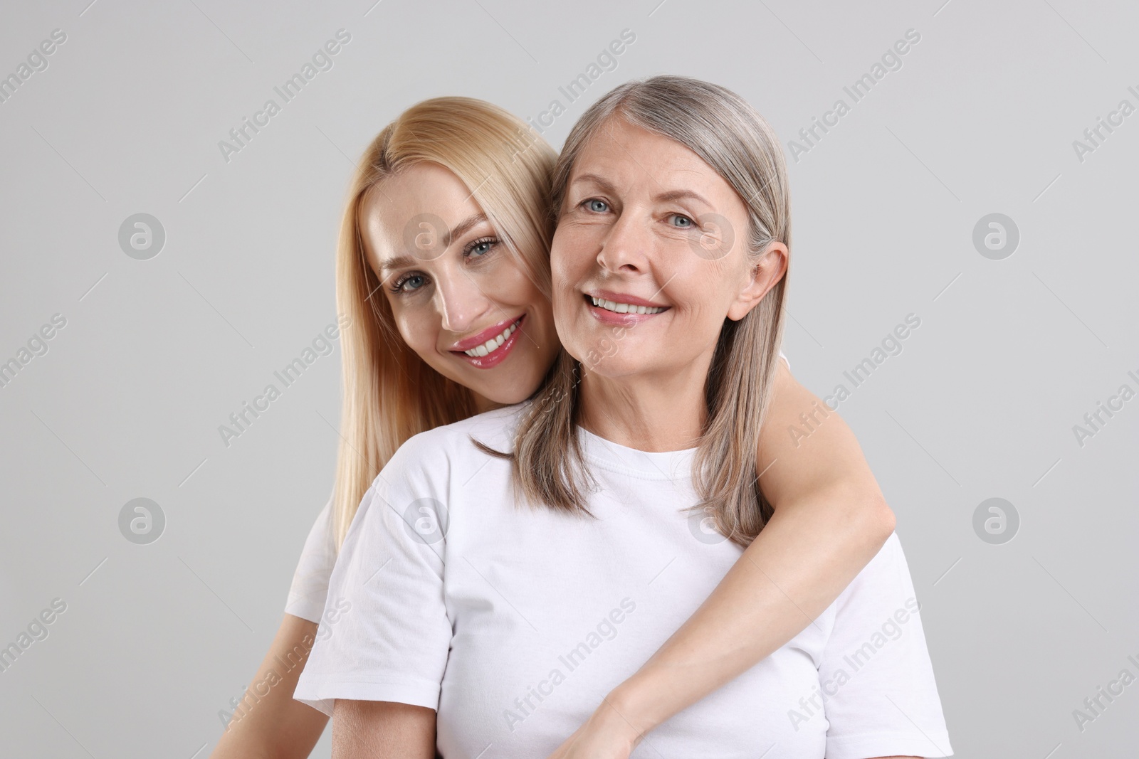 Photo of Family portrait of young woman and her mother on light grey background