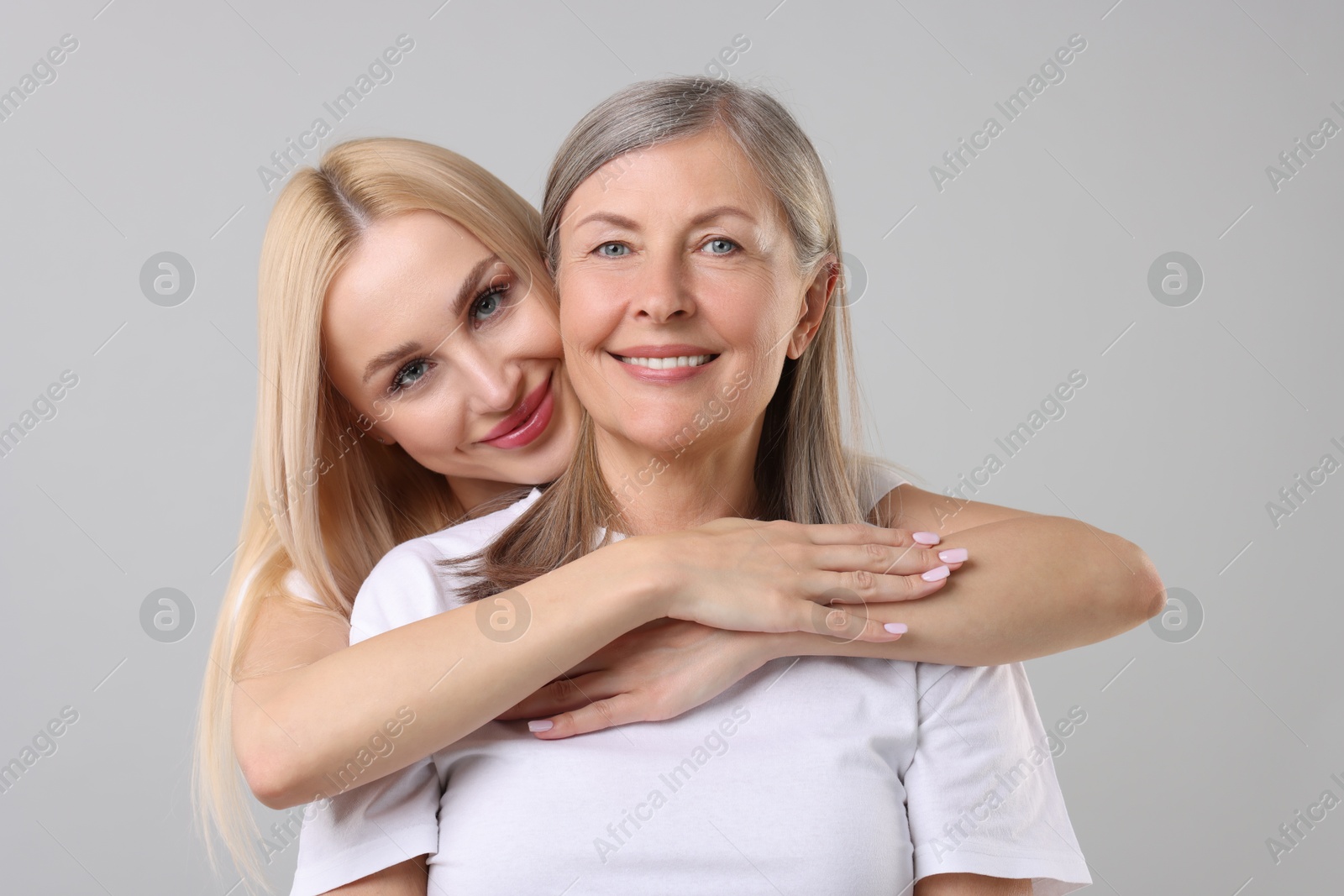 Photo of Family portrait of young woman and her mother on light grey background