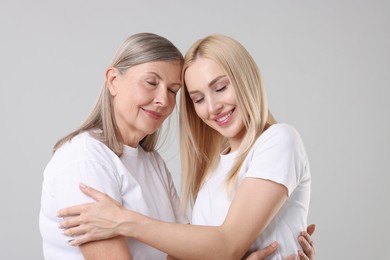 Photo of Family portrait of young woman and her mother on light grey background