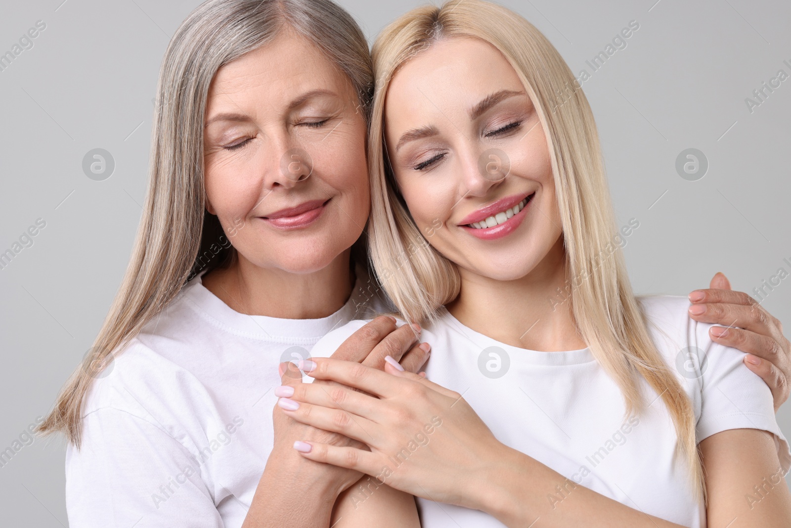 Photo of Family portrait of young woman and her mother on light grey background