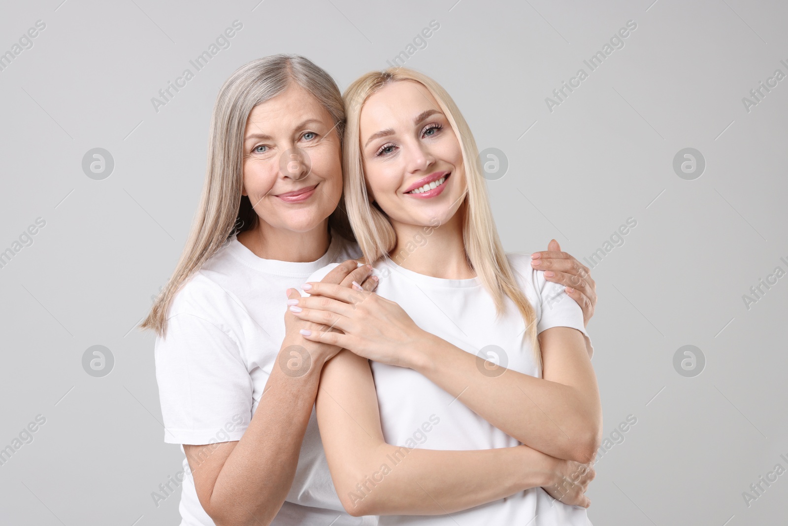 Photo of Family portrait of young woman and her mother on light grey background