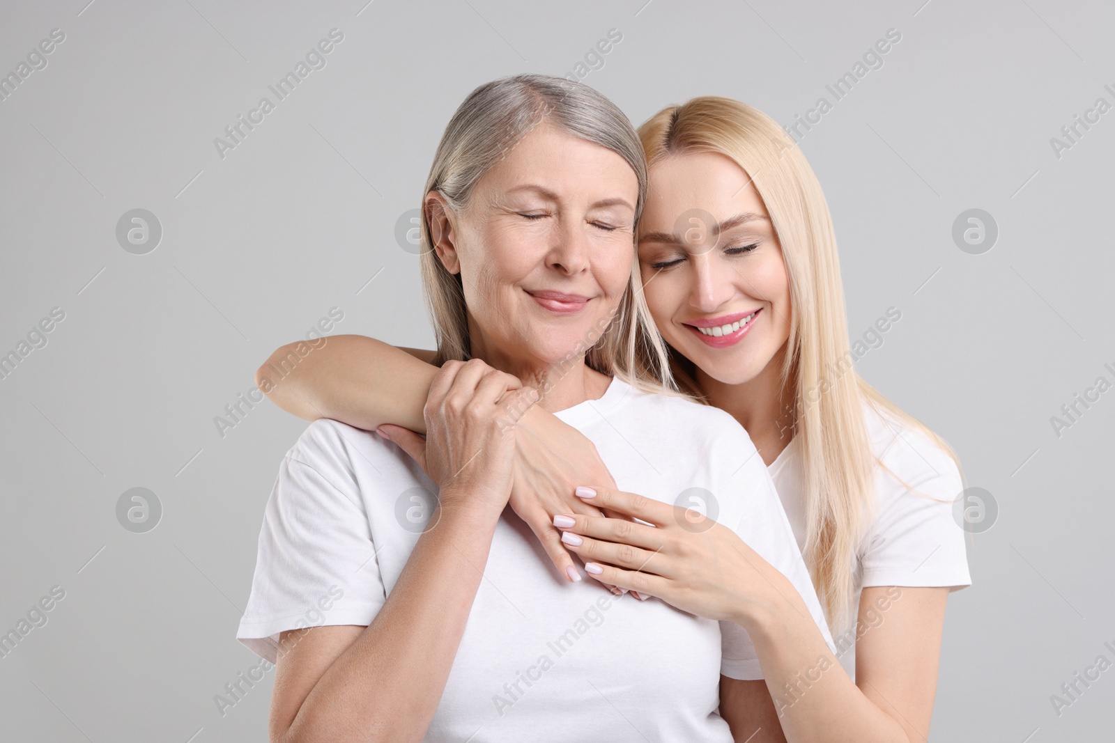 Photo of Family portrait of young woman and her mother on light grey background