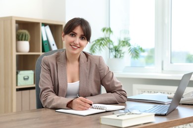 Portrait of smiling secretary at table in office