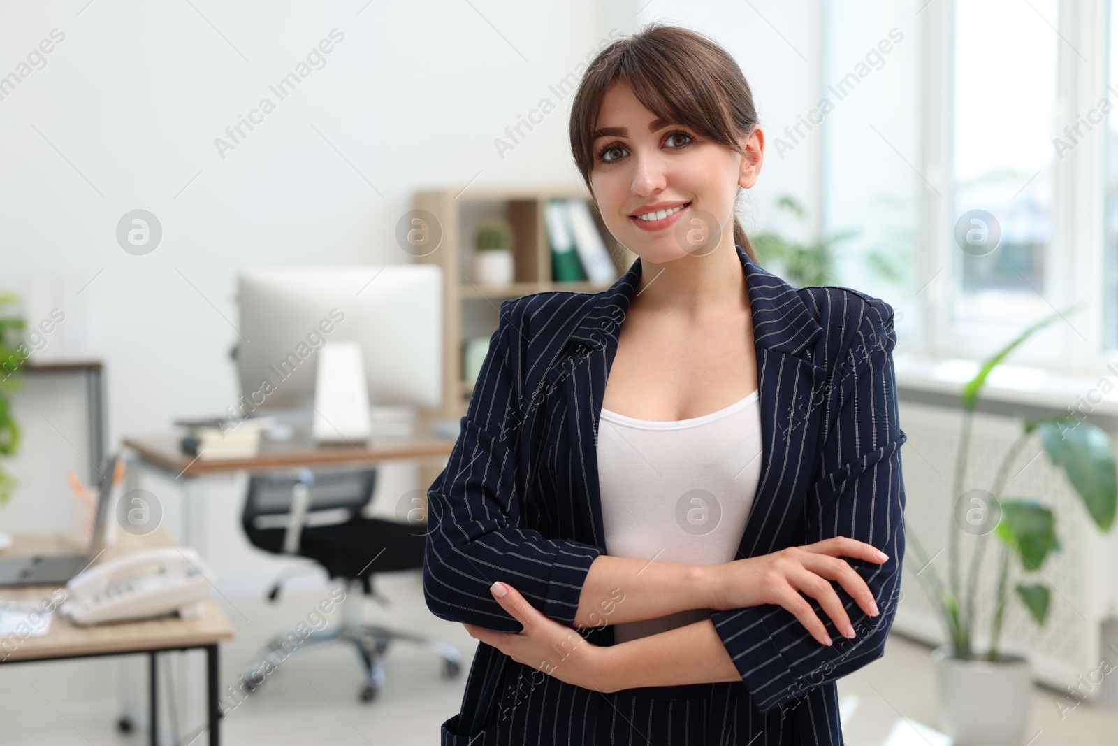 Photo of Portrait of smiling secretary with crossed arms in office