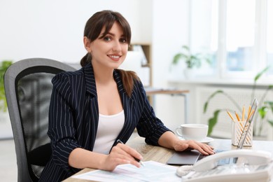 Portrait of smiling secretary at table in office